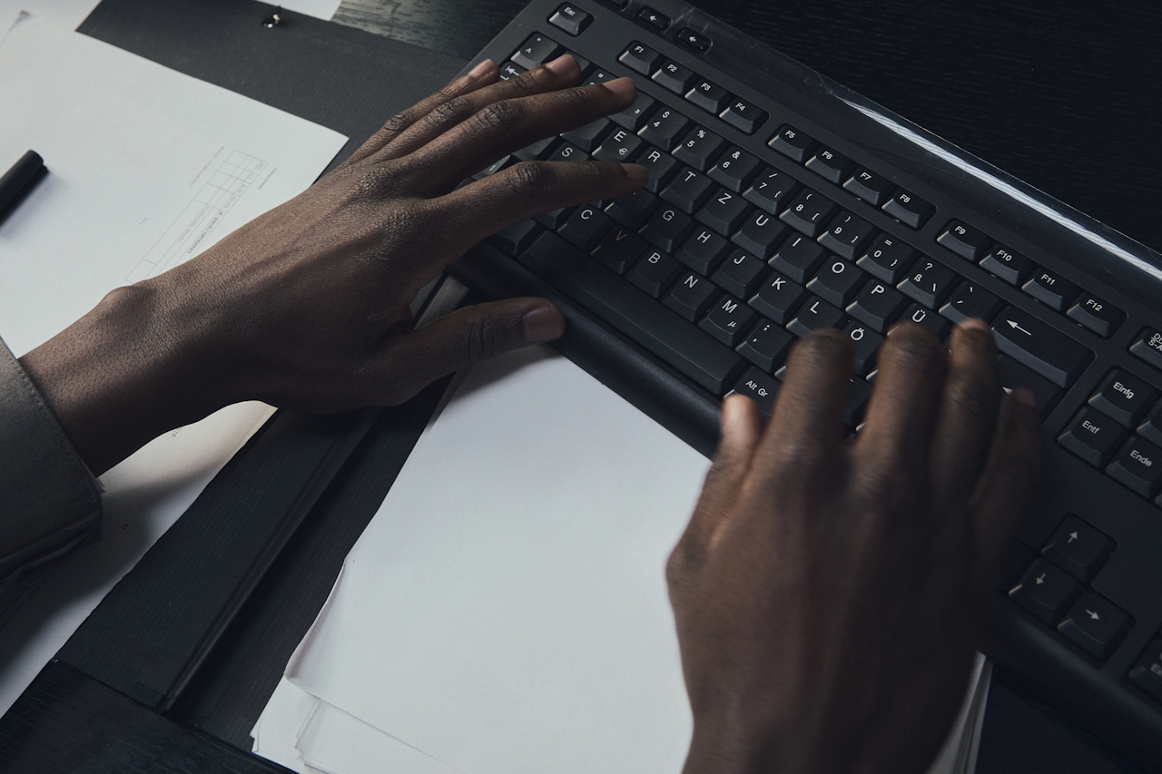 Hands typing on a keyboard with documents